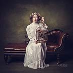 Young girl models posing in a old style fine art shoot while holding a birld cage for Cormac Byrne Photography, Limerick, Ireland.
  