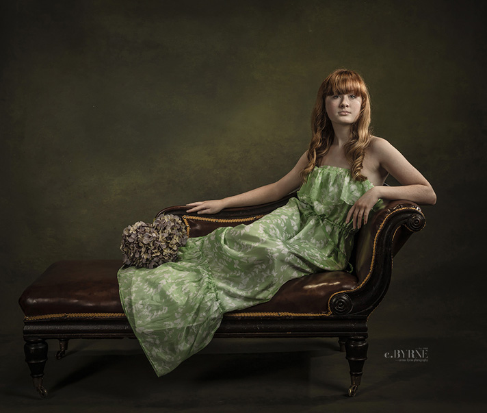 Portrait of girl in  a greeen dress on a chaise Longue.  